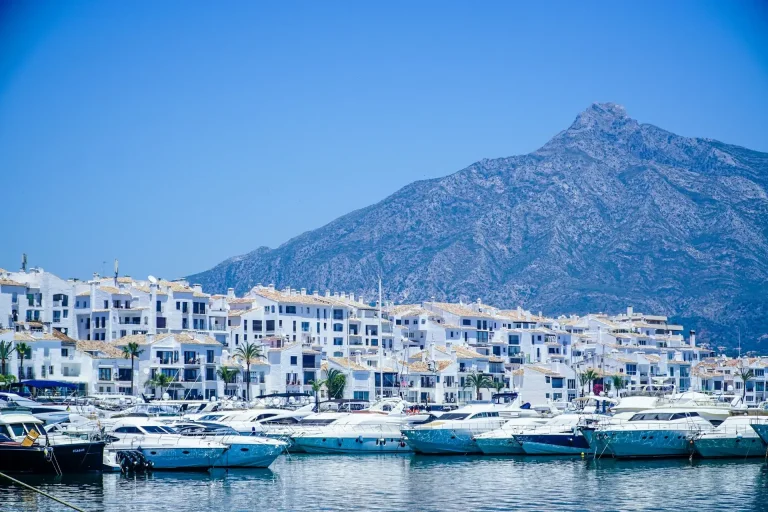 Bateaux blancs et bleus sur la mer près d'une montagne sous un ciel bleu en journée