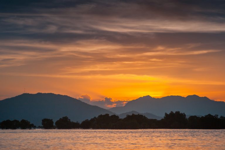 Silhouette de montagne près d'un plan d'eau au coucher du soleil.
