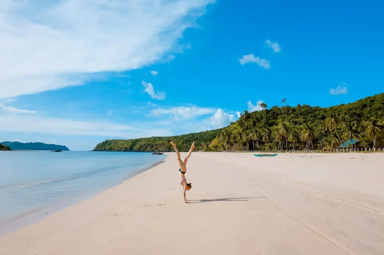 Femme faisant de l'acrobatie sur le rivage près d'une chaîne de montagnes.